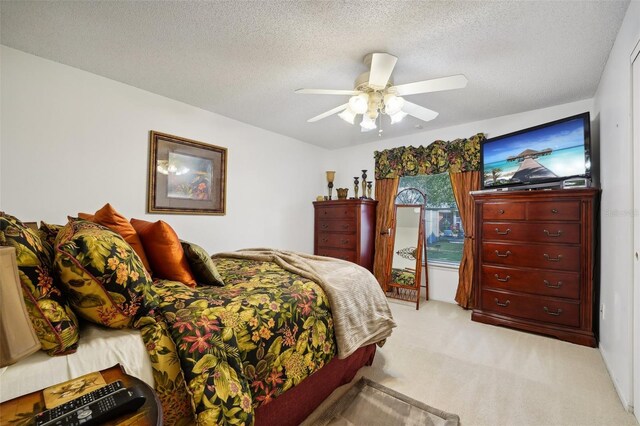 carpeted bedroom with ceiling fan and a textured ceiling