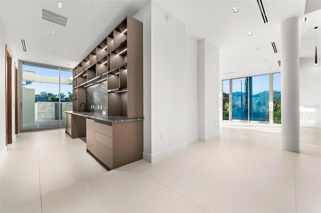 bar with light tile patterned floors, expansive windows, and dark stone countertops