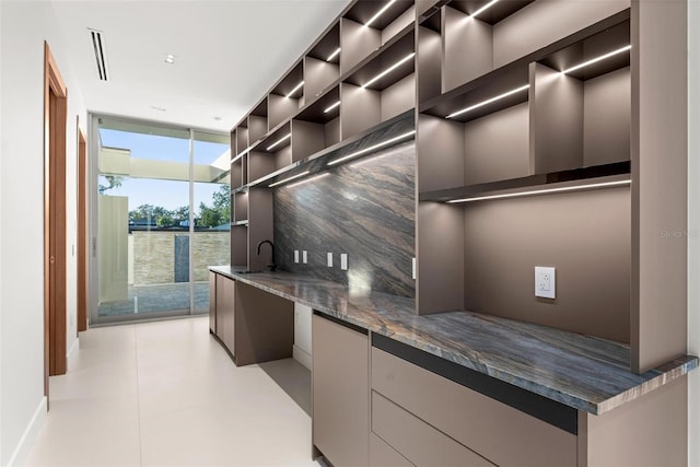 kitchen featuring decorative backsplash, dark stone countertops, a wall of windows, and sink