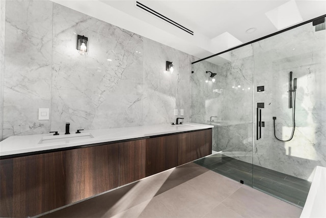 bathroom featuring tile patterned flooring, vanity, a shower with door, and tile walls