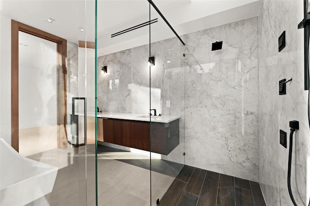 bathroom with a shower with door, vanity, and tile walls