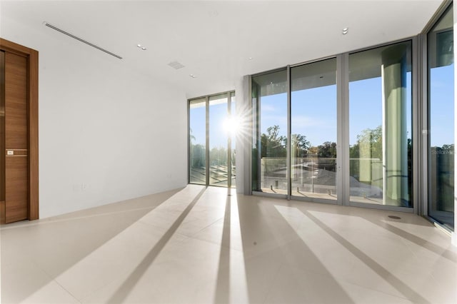 tiled empty room featuring a wall of windows