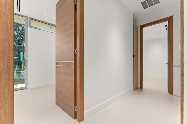 hallway with floor to ceiling windows, light tile patterned floors, and a healthy amount of sunlight