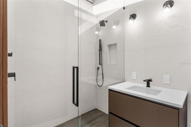 bathroom featuring wood-type flooring, vanity, walk in shower, and tile walls