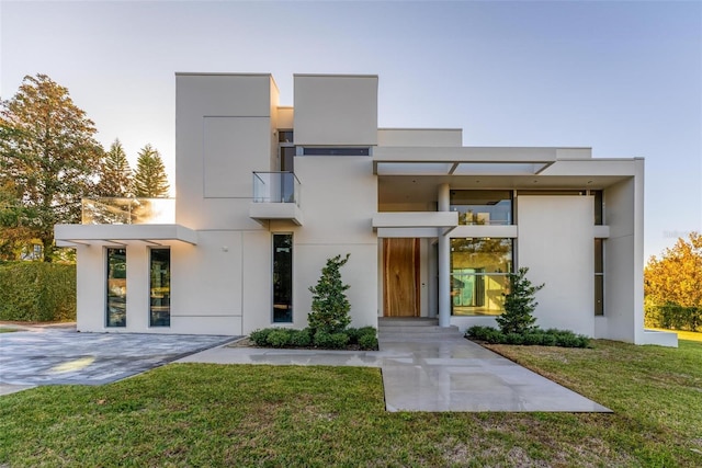 contemporary home featuring a balcony and a front lawn