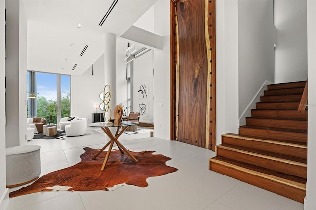 tiled foyer entrance with stairs and floor to ceiling windows