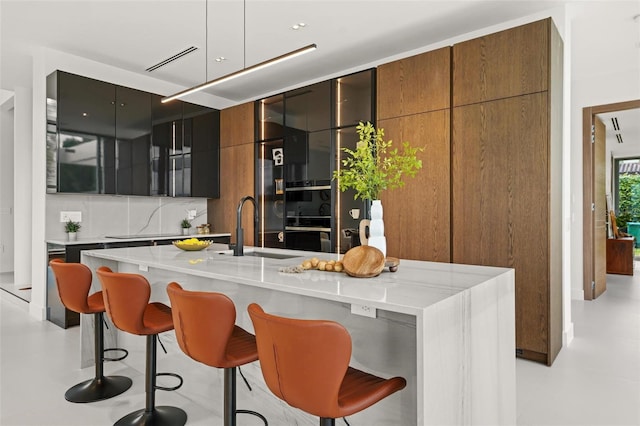 interior space with concrete flooring, backsplash, multiple ovens, and a sink