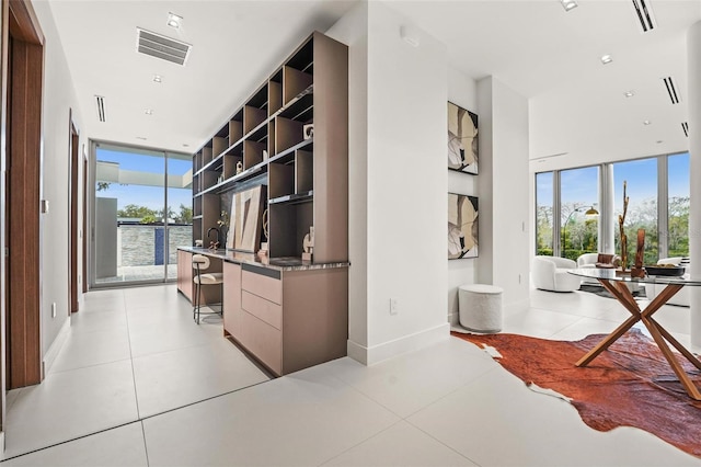 hallway featuring light tile patterned floors, baseboards, and visible vents