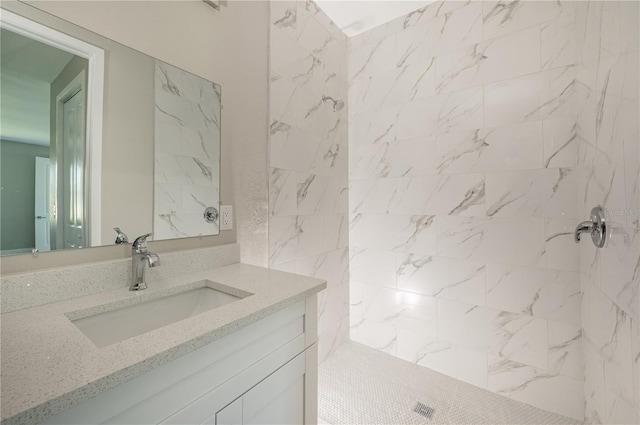 bathroom with tiled shower and vanity