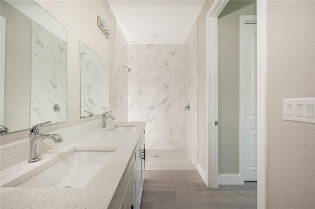 bathroom featuring hardwood / wood-style flooring, vanity, and a tile shower