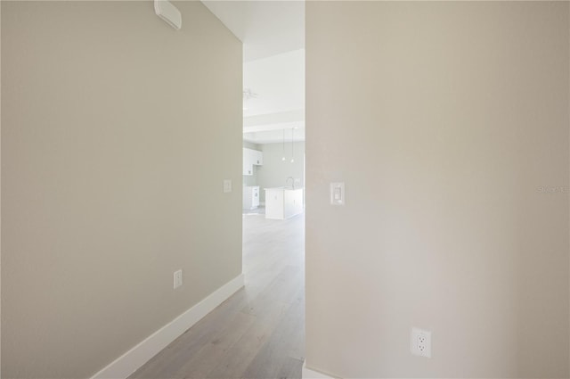 hallway with light wood-type flooring and sink