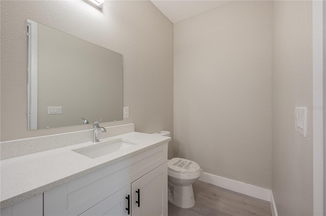 bathroom featuring wood-type flooring, vanity, and toilet