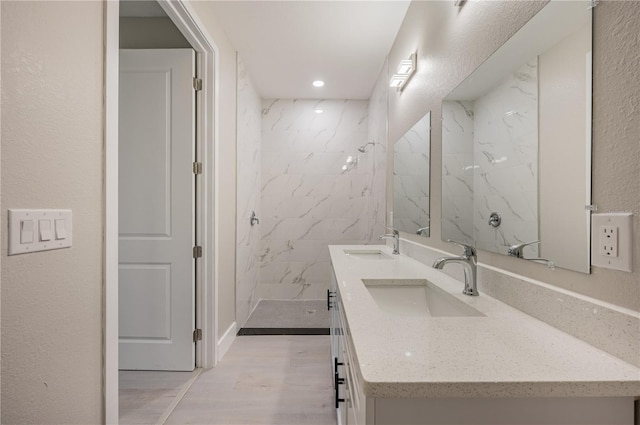 bathroom featuring hardwood / wood-style flooring, vanity, and tiled shower