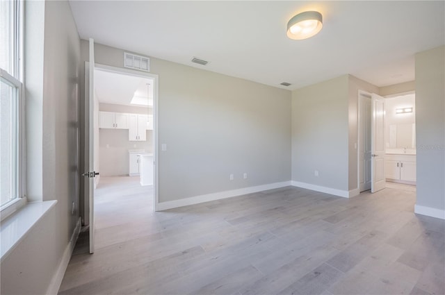 empty room with light hardwood / wood-style floors and a healthy amount of sunlight