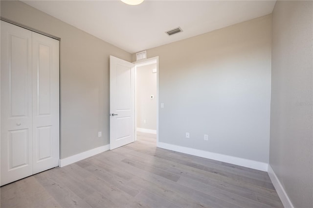 unfurnished bedroom featuring light hardwood / wood-style flooring and a closet