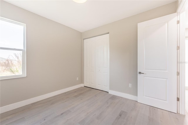 unfurnished bedroom featuring light hardwood / wood-style flooring and a closet