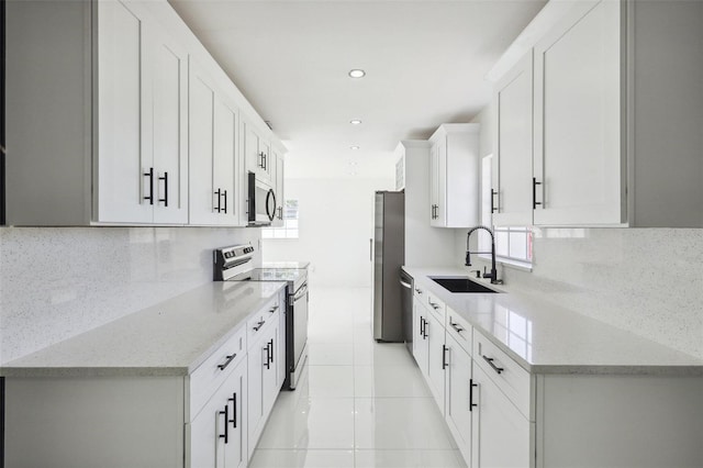 kitchen featuring white cabinets, appliances with stainless steel finishes, decorative backsplash, and sink