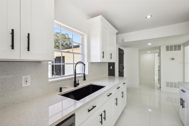 kitchen featuring sink, light stone counters, light tile patterned flooring, backsplash, and white cabinets