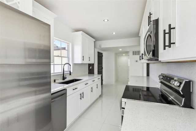 kitchen with white cabinetry, sink, light tile patterned flooring, and stainless steel appliances