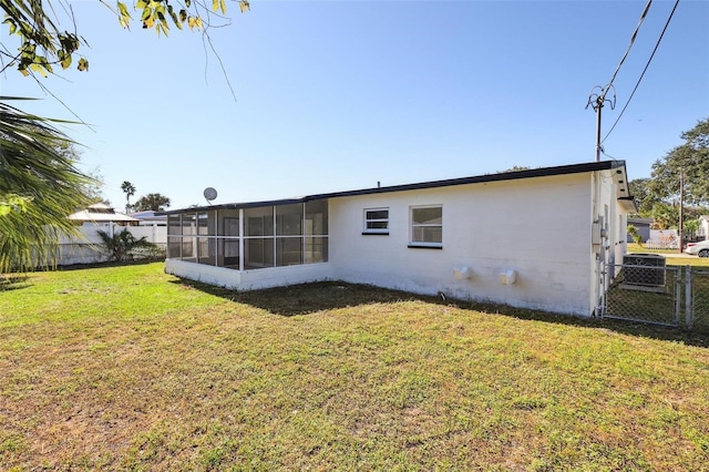 back of property featuring a sunroom and a lawn