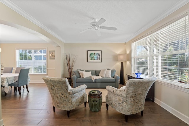 living room with dark hardwood / wood-style flooring, a wealth of natural light, and crown molding