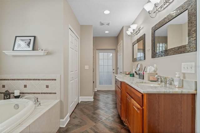 bathroom featuring a textured ceiling, vanity, tiled bath, and tile patterned floors