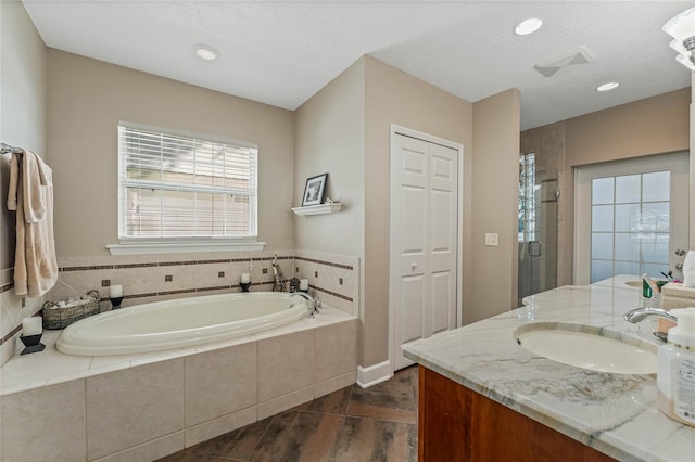 bathroom with vanity, separate shower and tub, and a textured ceiling