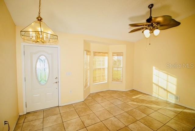 entrance foyer with light tile patterned flooring and ceiling fan with notable chandelier