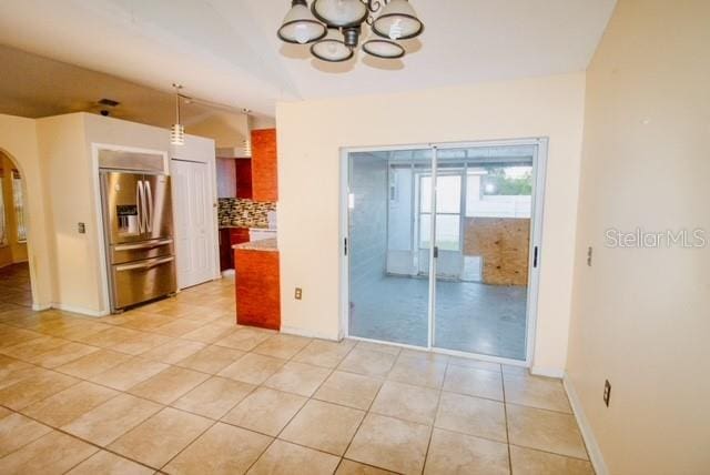 kitchen with lofted ceiling, decorative backsplash, light tile patterned floors, and stainless steel refrigerator with ice dispenser