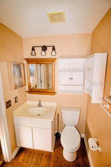 bathroom featuring vanity, hardwood / wood-style flooring, and toilet