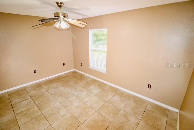 empty room featuring ceiling fan and tile patterned flooring