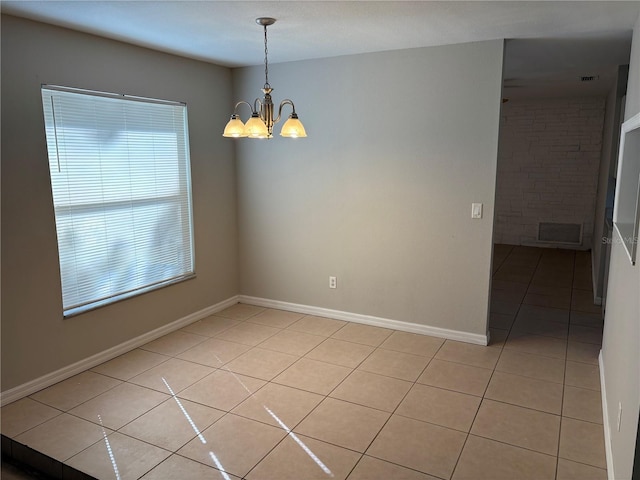 tiled empty room with an inviting chandelier