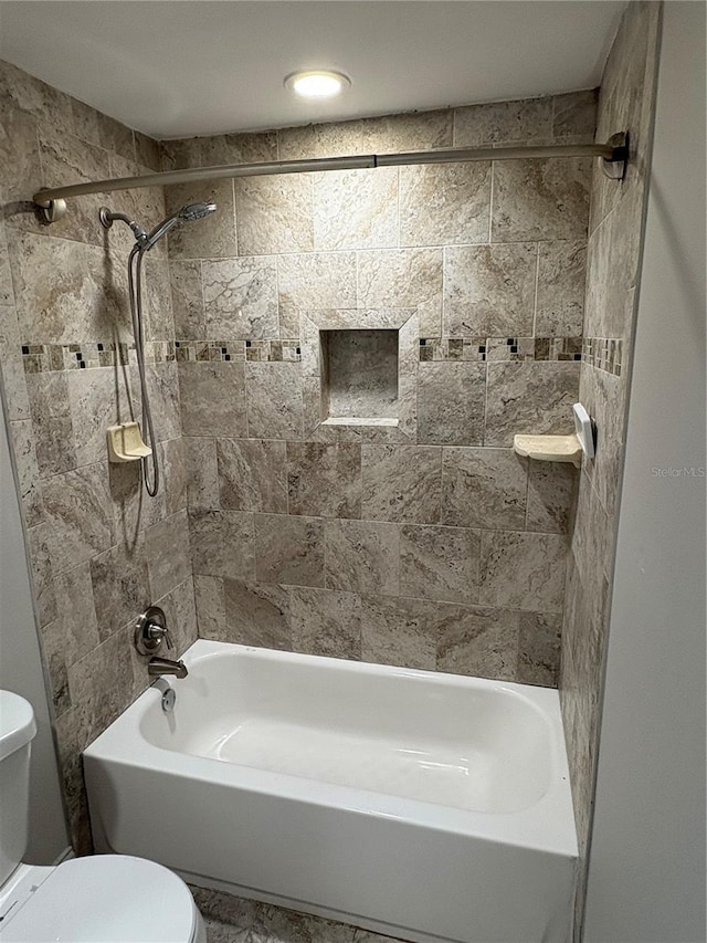 bathroom with tiled shower / bath and toilet