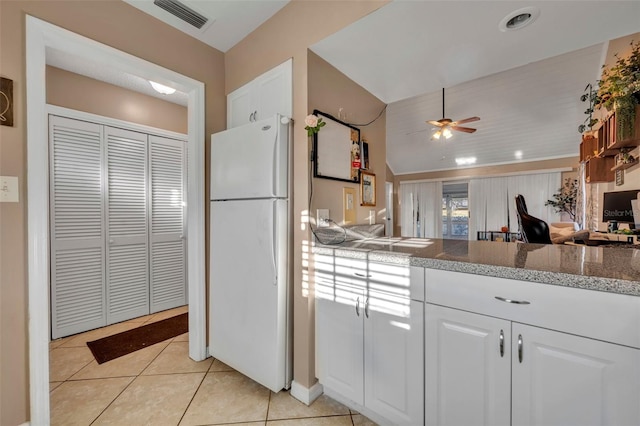 kitchen featuring white refrigerator, ceiling fan, light stone countertops, light tile patterned floors, and white cabinetry