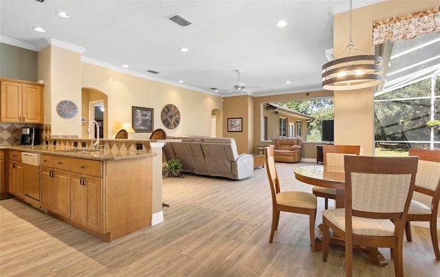 kitchen with dishwasher, sink, decorative light fixtures, and light hardwood / wood-style flooring