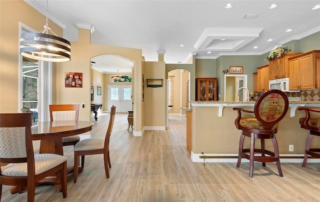 kitchen featuring decorative backsplash, light stone counters, crown molding, a notable chandelier, and light hardwood / wood-style floors