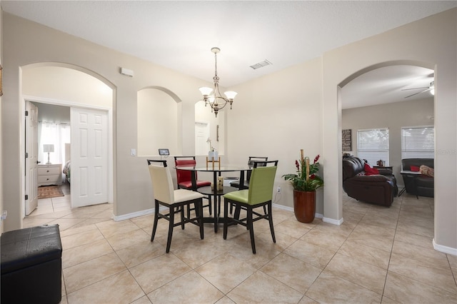 dining room with light tile patterned floors and ceiling fan with notable chandelier