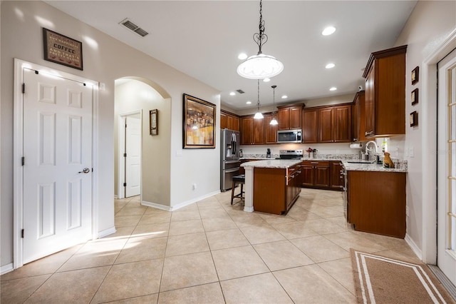 kitchen with a center island, a breakfast bar area, decorative light fixtures, light stone counters, and stainless steel appliances