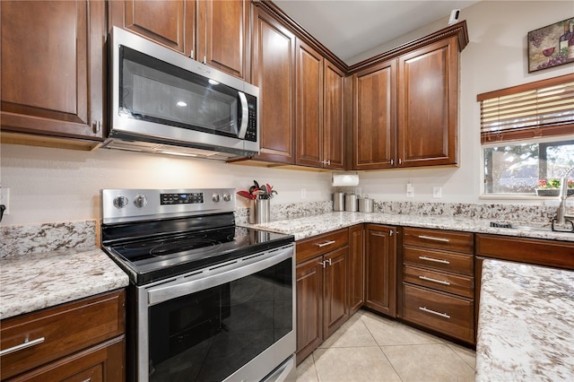 kitchen with light stone countertops, sink, light tile patterned floors, and appliances with stainless steel finishes