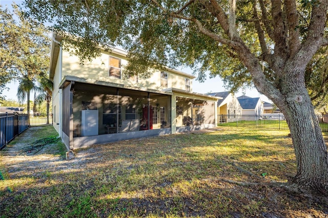 rear view of house featuring a lawn and a sunroom