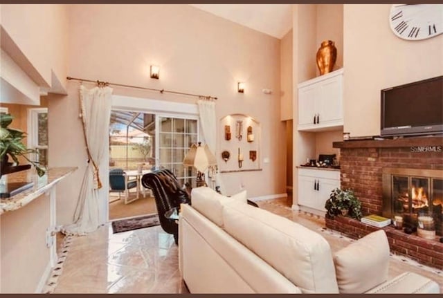 living room featuring a brick fireplace and a high ceiling