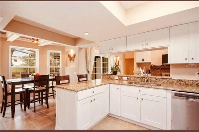 kitchen featuring sink, light stone counters, stainless steel dishwasher, kitchen peninsula, and white cabinets