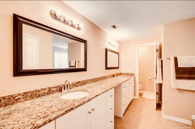 bathroom featuring vanity, toilet, and a textured ceiling