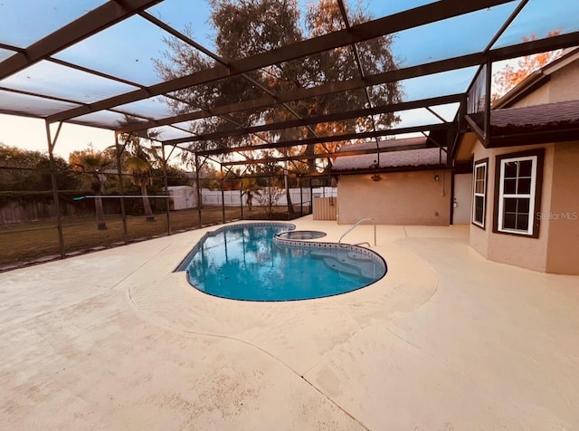 pool at dusk featuring a lanai, a hot tub, and a patio