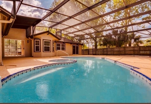 pool at dusk featuring an in ground hot tub, glass enclosure, and a patio area