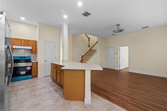 kitchen featuring decorative backsplash, a kitchen island, light wood-type flooring, and appliances with stainless steel finishes