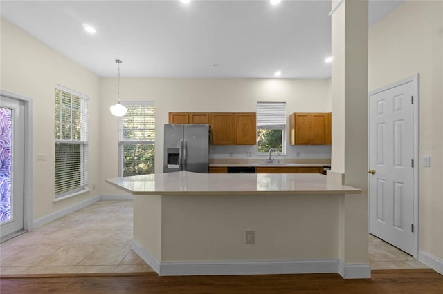 kitchen with sink, hanging light fixtures, light tile patterned floors, plenty of natural light, and stainless steel fridge with ice dispenser