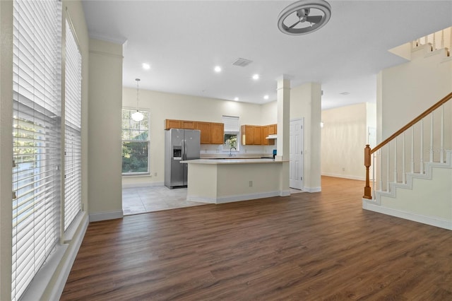 kitchen featuring a wealth of natural light, hanging light fixtures, dark hardwood / wood-style floors, stainless steel refrigerator with ice dispenser, and a kitchen island