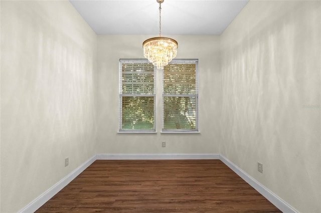 unfurnished room with a notable chandelier and dark hardwood / wood-style floors