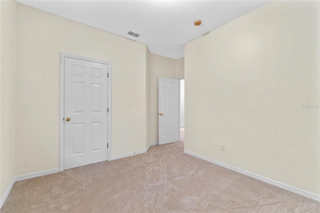 carpeted empty room with a textured ceiling